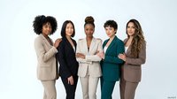 Group of five diverse women in professional business attire standing together against white background for corporate team, leadership, and workforce concepts.