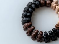 Carved wooden bracelet featuring alternating black and brown elephant beads on white background, spiritual jewelry piece for meditation and mindfulness practice.