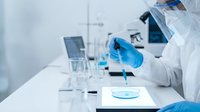 Scientist in protective gear conducting laboratory research with test tubes and equipment in modern medical facility for pharmaceutical development.