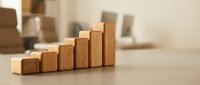 Wooden blocks arranged in ascending staircase pattern symbolizing growth, progress, and business success on neutral surface for corporate presentations.