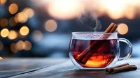 Steaming hot tea with cinnamon sticks in glass cup against blurred bokeh lights background, cozy winter evening atmosphere with aromatic spices.
