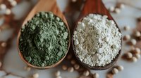 Green and white superfood powders in wooden spoons, close up view of organic supplements and natural ingredients for healthy nutrition and wellness.