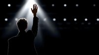 Male performer silhouette with raised hand on stage under bright spotlight with bokeh lights background for concerts and entertainment events.