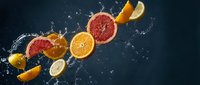Fresh citrus fruits with water splash on dark background for healthy nutrition and vitamin C concepts.