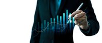 Professional businessman in dark suit drawing upward trending financial graph with glowing blue data visualization charts for business growth analysis.