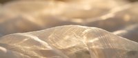Smooth golden sand dunes with soft shadows and warm sunlight creating natural patterns and textures in desert landscape for travel and nature concepts.