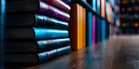 Row of colorful book spines on wooden shelf with soft bokeh background, selective focus on blue and purple volumes creating atmospheric library scene.