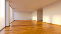Empty modern room interior with hardwood flooring and large windows creating natural light patterns on white walls for residential design.