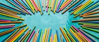 Colorful pencils arranged in circular pattern on turquoise textured background creating vibrant frame for creative projects and artistic designs.