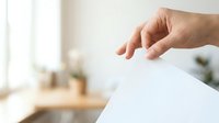 Person with light skin tone inserting blank white paper into slot, suggesting voting, feedback, or document submission in bright office setting.