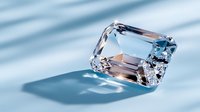 Clear emerald cut diamond gemstone casting soft blue shadows on minimal background. Luxury jewelry concept with brilliant crystal refraction and light play.