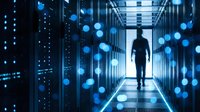Male IT engineer walking through a dark server room corridor with glowing blue data nodes, representing cloud computing and network security.