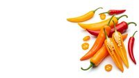 Fresh colorful chili peppers in yellow, orange and red varieties arranged on white background with copy space for culinary and cooking designs.