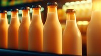 Glass bottles filled with fresh orange juice or smoothie arranged in row on dark background with warm ambient lighting and bokeh effect.