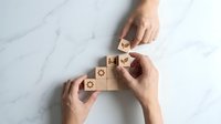 Hands arranging wooden blocks with star symbols on marble surface, building step-by-step structure for business growth and achievement concept.