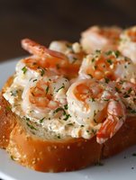 Succulent shrimp salad served on toasted brioche bread, garnished with fresh chopped herbs. Creamy seafood appetizer showcases delicate pink prawns and mayo dressing.