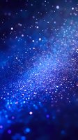 Magical blue glitter particles with bokeh effect on dark background, sparkling and shimmering with depth of field for festive designs and celebrations.