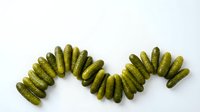 Isolated gherkins and pickled cucumbers arranged in curved lines on white background, ready for food packaging, recipe blogs, grocery advertising and culinary design projects.