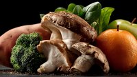 Fresh organic vegetables, mushrooms, and fruits arranged on dark background for healthy eating and cooking ingredients.