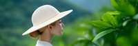 Young woman in white sun hat enjoying peaceful moment in lush green tropical garden setting with soft natural lighting and serene atmosphere.