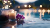 Glowing candle and purple orchid flower at poolside with bokeh lights in evening, creating tranquil spa atmosphere near swimming pool water surface.