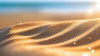 Glowing golden sand dunes with sparkling water drops in soft sunlight creating magical bokeh effect and dreamy waves pattern. Macro nature photography.