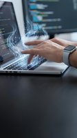 Programmer hands typing on laptop with digital data stream and binary code overlay. Software development and coding concept for tech presentations.