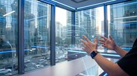 Professional businesswoman gesturing during presentation in modern office with panoramic city view through floor-to-ceiling windows.