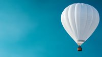 White hot air balloon floating in bright turquoise sky, minimalist composition with copy space for text, adventure and freedom concept.