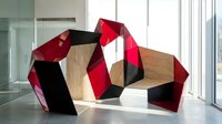 Modern geometric wooden furniture with red and black angular design in contemporary office interior space for creative workspace solutions.