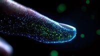 Glowing fiber optic tip emitting blue and green light particles against dark background, macro photography showing detailed illuminated technology elements.