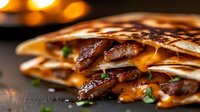 Grilled quesadilla with tender steak strips, melted cheddar cheese and fresh herbs on dark background, close up view with selective focus and warm lighting.