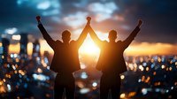 Two silhouetted men raise arms victoriously against dramatic sunset cityscape with glowing bokeh lights, celebrating success and achievement in business.