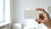Caucasian male hand holding blank white business card against blurred office background, suitable for branding, corporate identity, and business marketing materials.