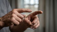 Elderly hands with age spots gesturing in conversation, showing wrinkled skin and natural aging process in soft indoor lighting for healthcare concepts.