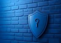 Shield with keyhole icon on blue brick wall background represents data protection and cybersecurity concept for business and technology solutions.