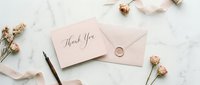 Elegant pink thank you card with wax seal envelope, dried roses, and ribbon on marble background, perfect for wedding stationery.