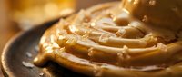 Creamy peanut butter swirl on dark plate with smooth texture, ideal for food photography, culinary content, and recipe illustrations.