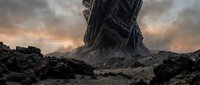 Massive futuristic tower structure emerging from barren rocky landscape under dramatic cloudy sky, suitable for sci-fi, gaming, and fantasy concept art projects.