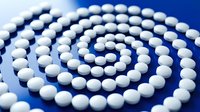 White pharmaceutical pills arranged in spiral pattern on blue background for medical healthcare and medication concepts.
