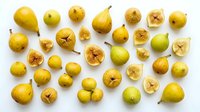 Assorted fresh yellow pears and cross-sections arranged on white background, showing whole fruits and sliced interiors for food styling, culinary, and ingredient photography use.