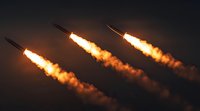 Three glowing missiles or rockets flying in parallel formation against dark sky with bright orange exhaust trails and smoke creating dramatic night scene.