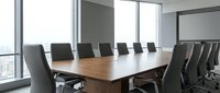 Modern corporate boardroom with wooden conference table and black leather chairs overlooking city skyline through floor-to-ceiling windows for business meetings.