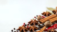 Aromatic spices collection with cinnamon sticks, star anise, nutmeg and peppercorns arranged on white background for culinary and cooking projects.