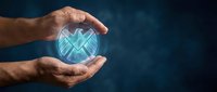 Male hands holding glowing digital shield with checkmark symbol against dark blue background, representing cybersecurity, data protection, and network safety for technology concepts.