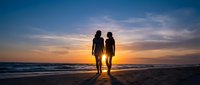 Romantic couple silhouettes walking hand in hand on beach at sunset with golden sky and ocean waves for love and relationship concepts.