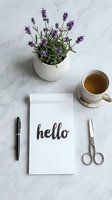 Flat lay of a notepad with hello lettering, lavender plant, tea cup, pen and scissors on marble surface for lifestyle blogs.