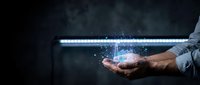 Businessman holding glowing digital light beam with sparkling particles emerging from palm against dark background for technology presentations.