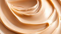 Smooth swirls of creamy beige caramel sauce or melted white chocolate creating elegant waves and curves against light background, macro food photography.