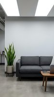 Modern minimalist living room with gray upholstered sofa, potted snake plant, wooden coffee table, and skylight ceiling. Ideal for interior design, home decor, and contemporary space concepts.